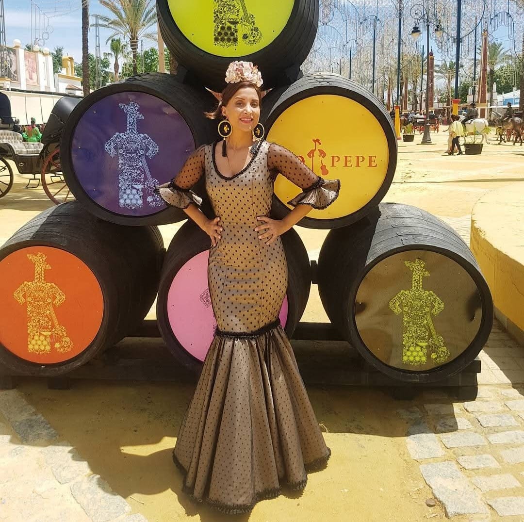 Vestido negro elegante en la Feria de Jerez con barriles de Tío Pepe