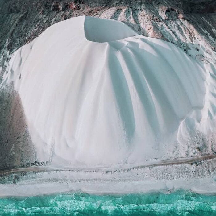 Duna de arena blanca cayendo suavemente al mar turquesa y cristalino en Socotra, bajo el sol del Índico.