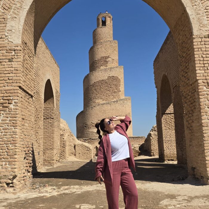 Viajera contemplando el minarete espiral Al-Malwiya al atardecer en Samarra, Irak. Fotografía cálida que representa historia, espiritualidad y belleza del país.