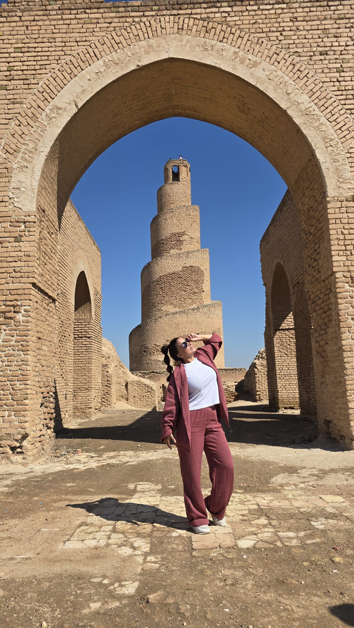 Viajera contemplando el minarete espiral Al-Malwiya al atardecer en Samarra, Irak. Fotografía cálida que representa historia, espiritualidad y belleza del país.